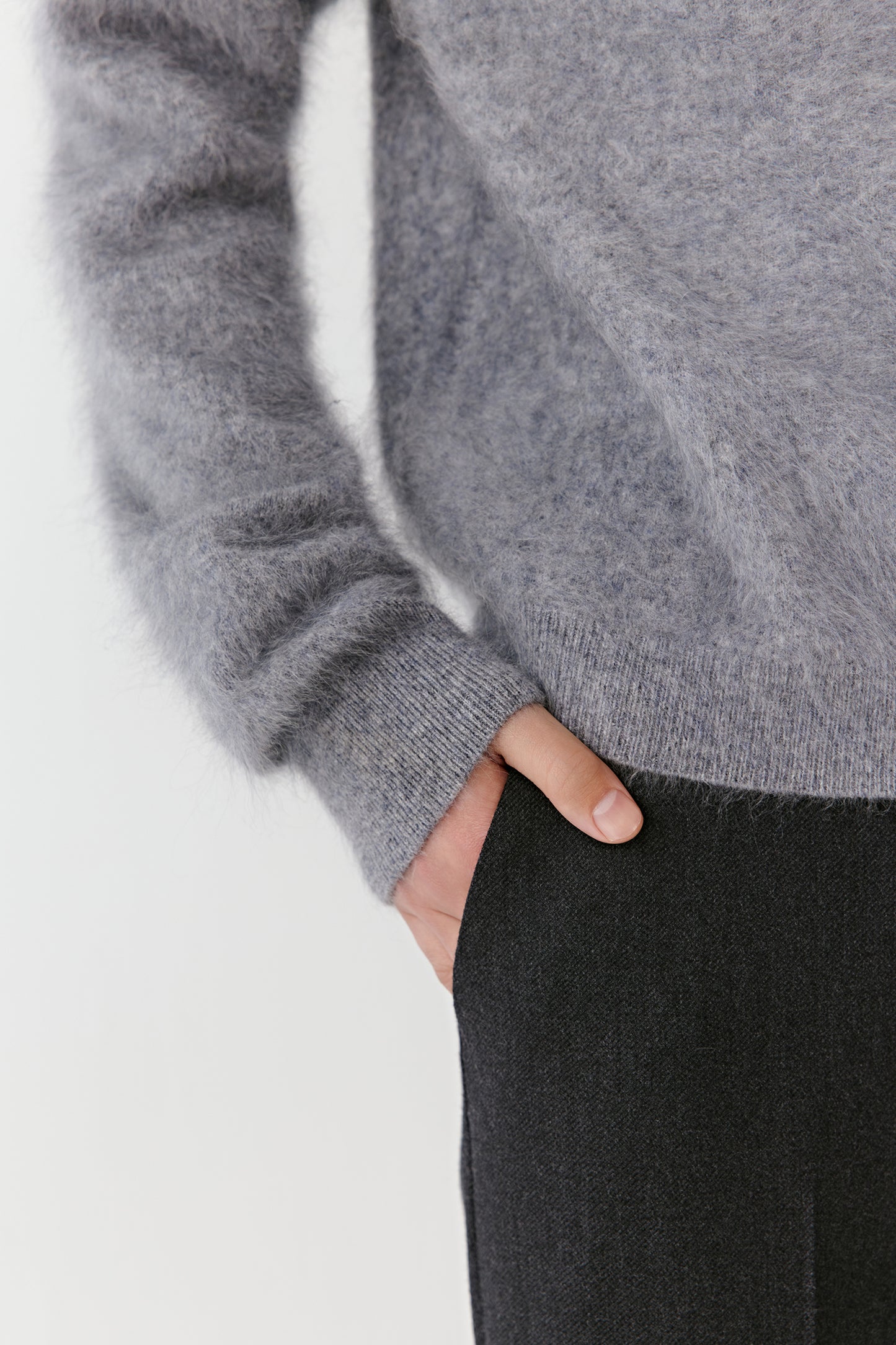 Detail view of the sleeve and pocket of a grey cashmere cardigan.