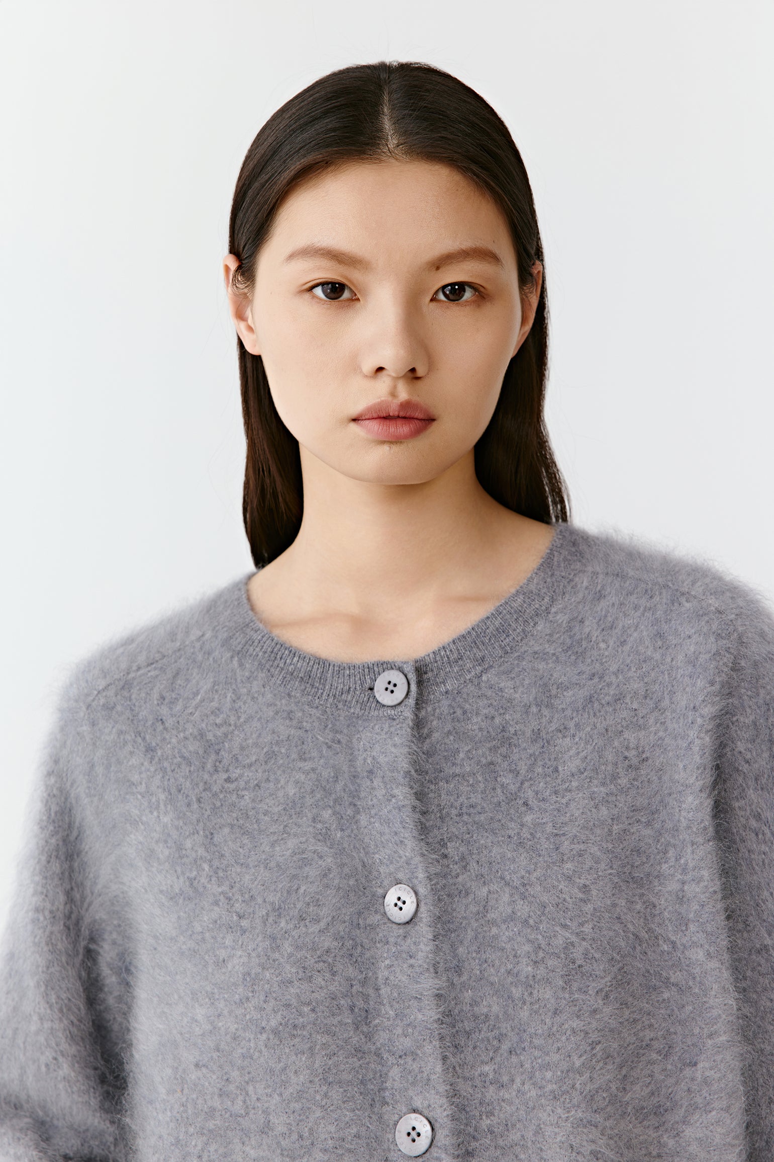 Close-up of a woman wearing a grey cashmere cardigan with fine knit texture.