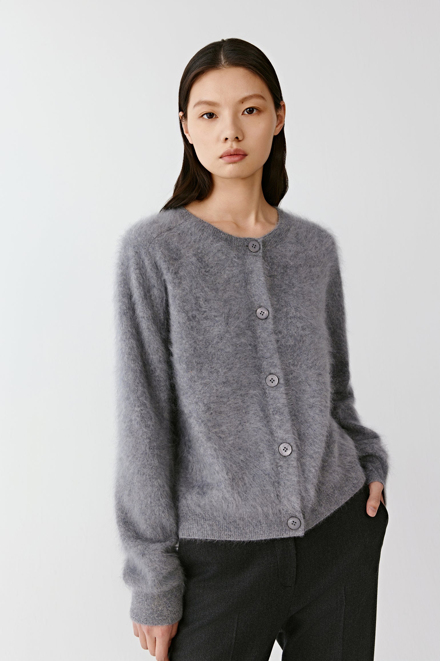 Front view of a woman wearing a grey cashmere cardigan with front buttons and ribbed edges.