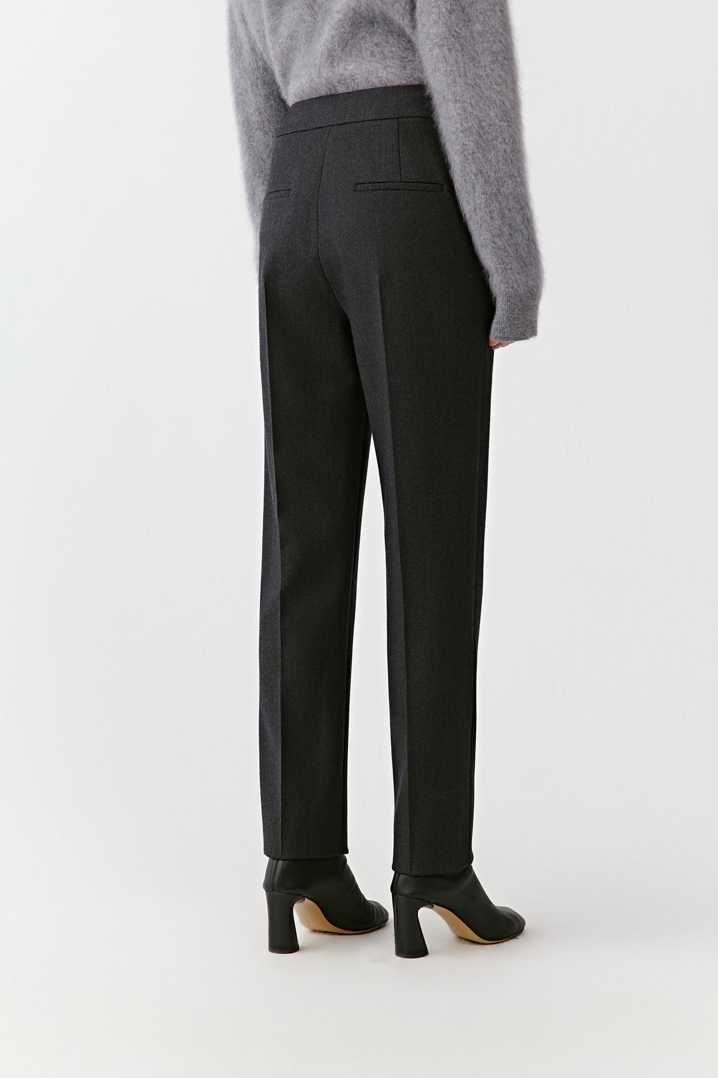 Side angle of the outfit showing the straight cut of the black pants and relaxed drape of the gray sweater.