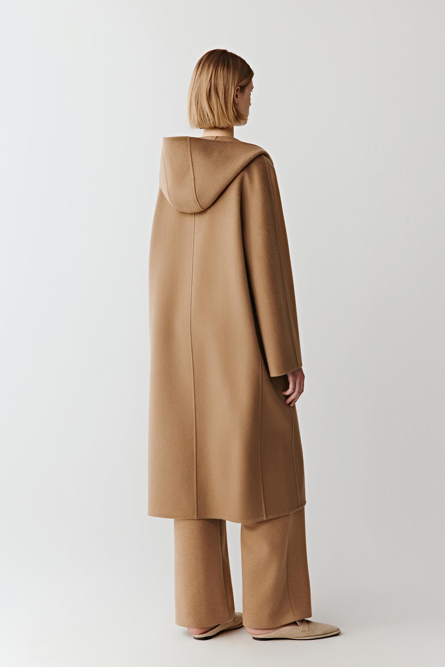 Back view of the camel wool coat highlighting its mid-calf length and smooth, structured drape.