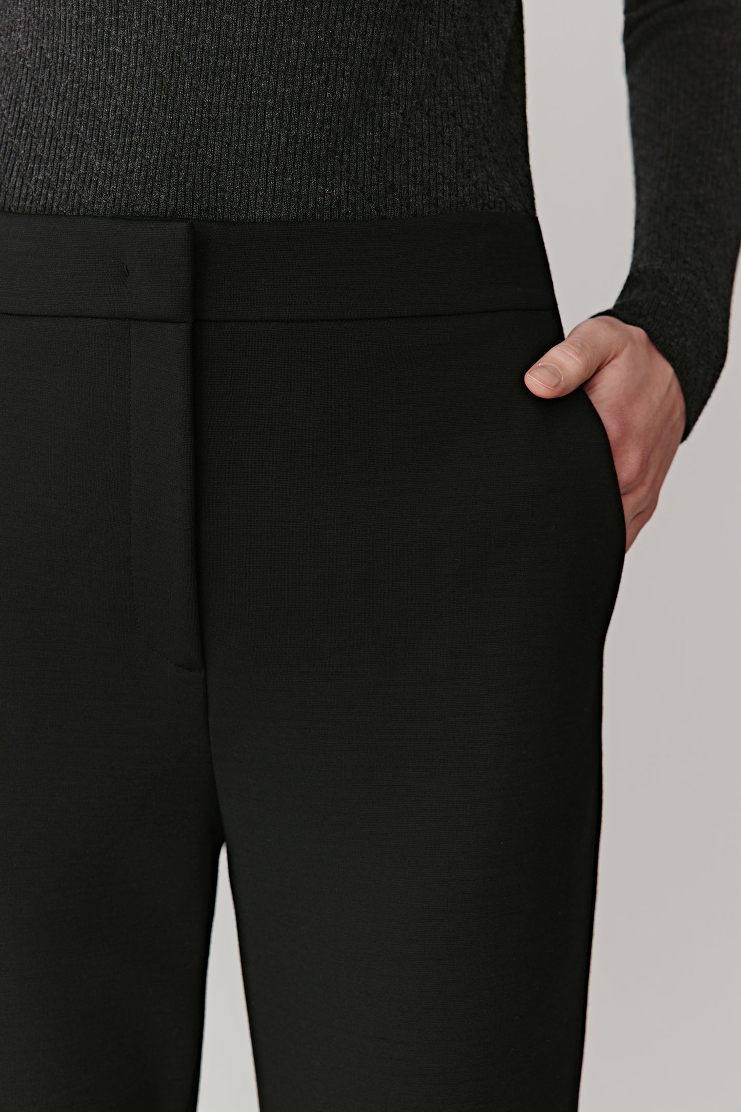 Close-up of the waistband and front pleats highlighting the dense Ponte-de-Roma texture and discreet pockets.