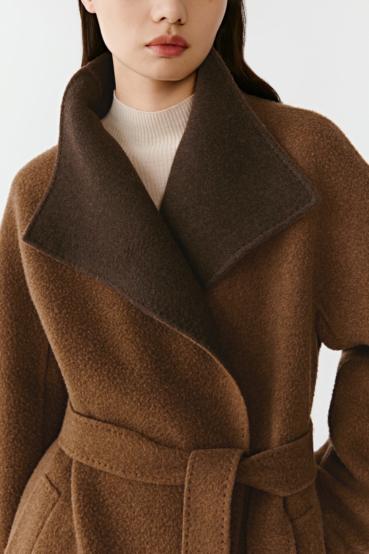 A macro image focuses on the neckline and double-faced finish, showing the refined craftsmanship and warm tones of the fabric.