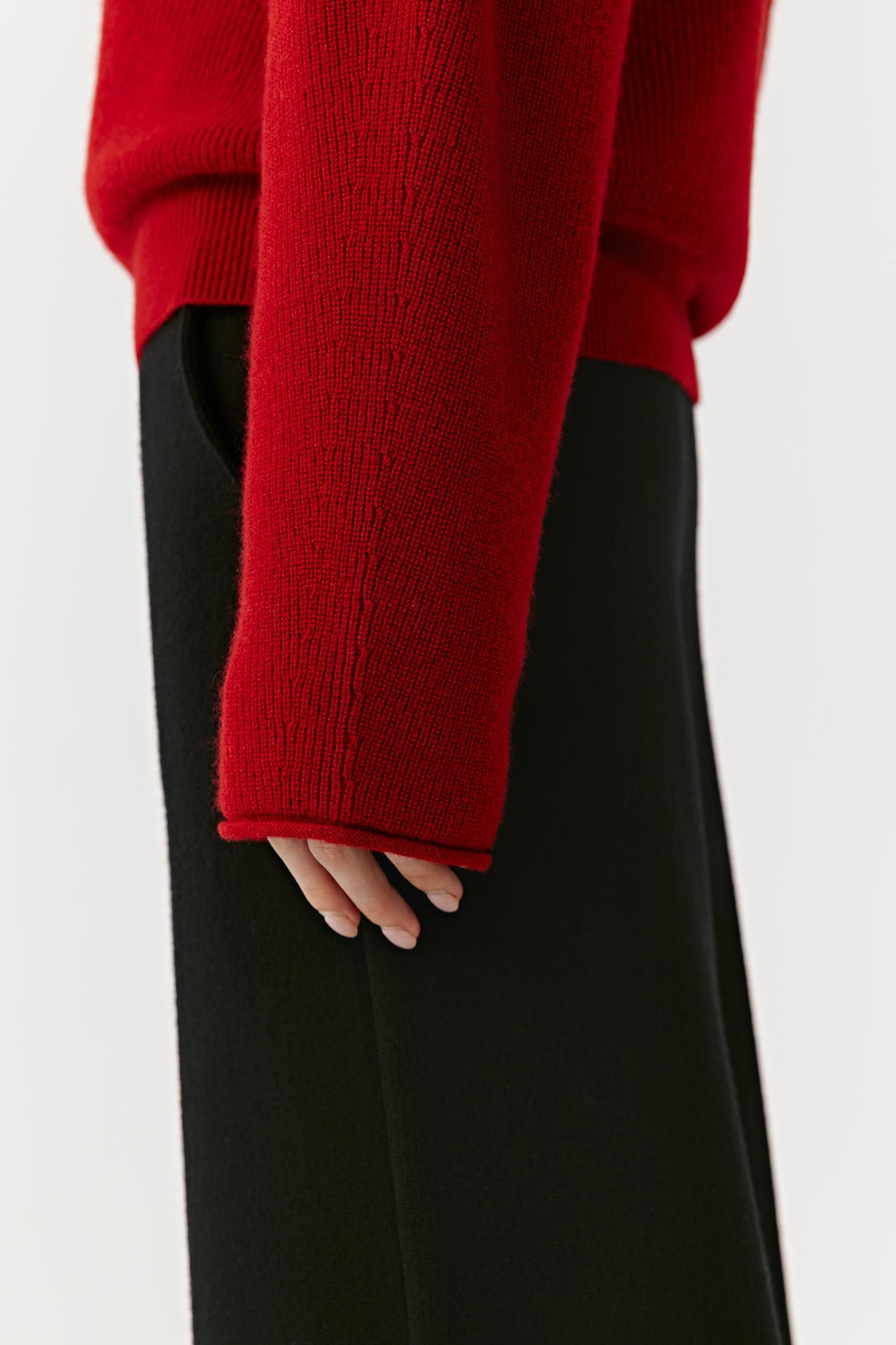 Detail close-up of the sleeve and cuff of the red cashmere pullover.