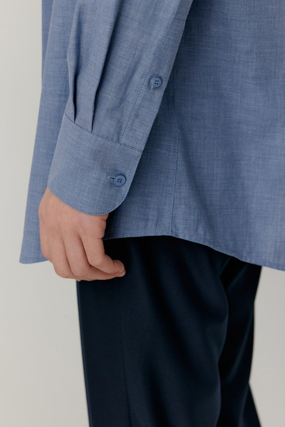Close-up of the long sleeve and buttoned cuff of the light blue cotton shirt.