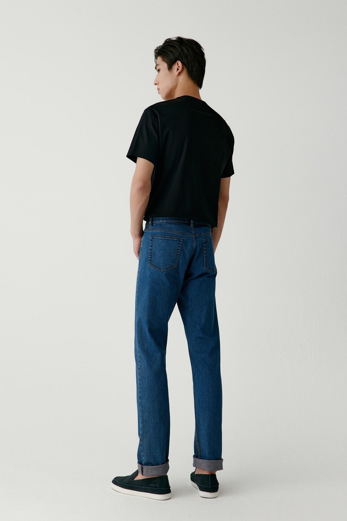 A three-quarter view captures the movement as he turns slightly, revealing the straight cut and natural drape.