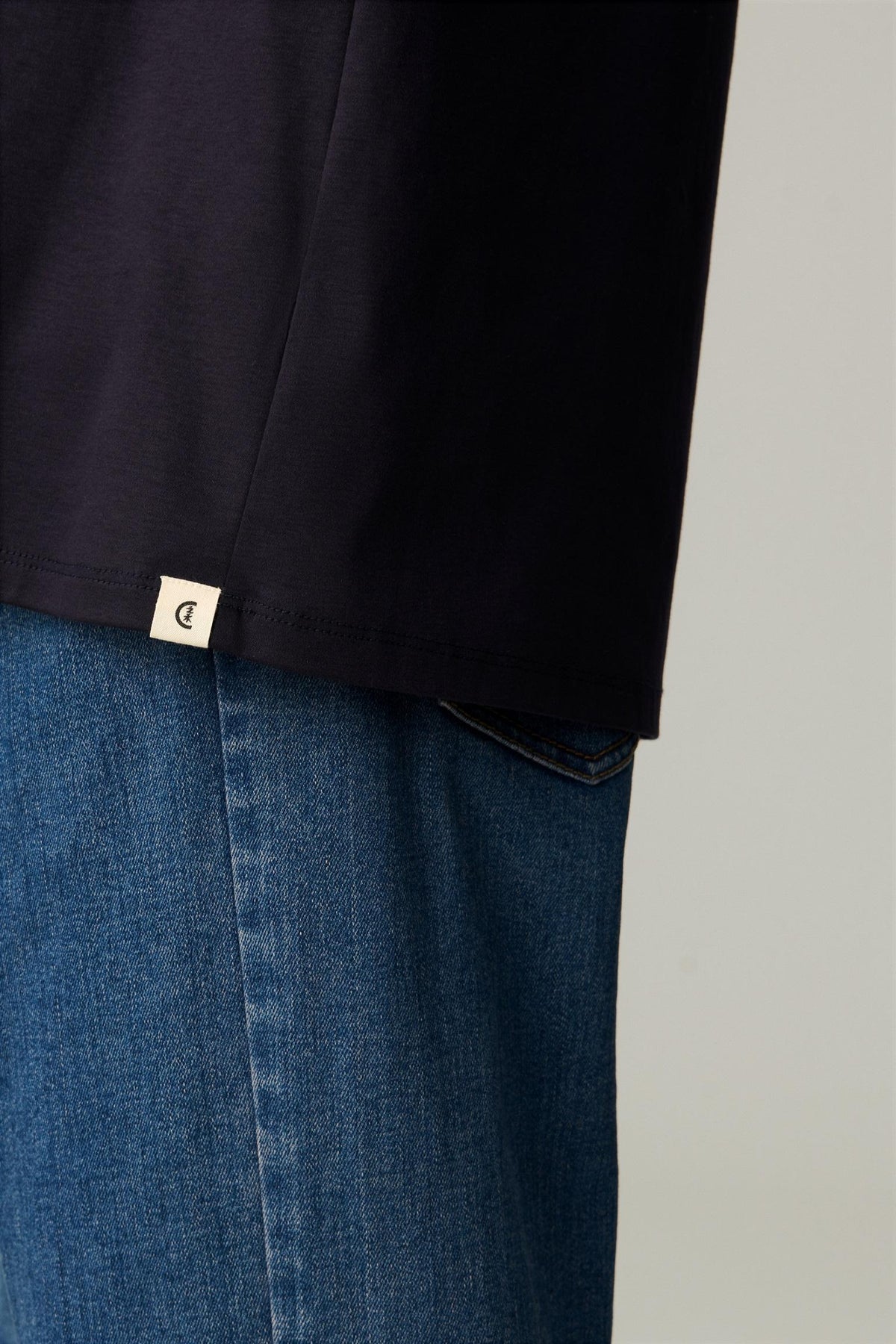 Close-up of the hem of the deep navy blue cotton T-shirt, showing the clean finish.