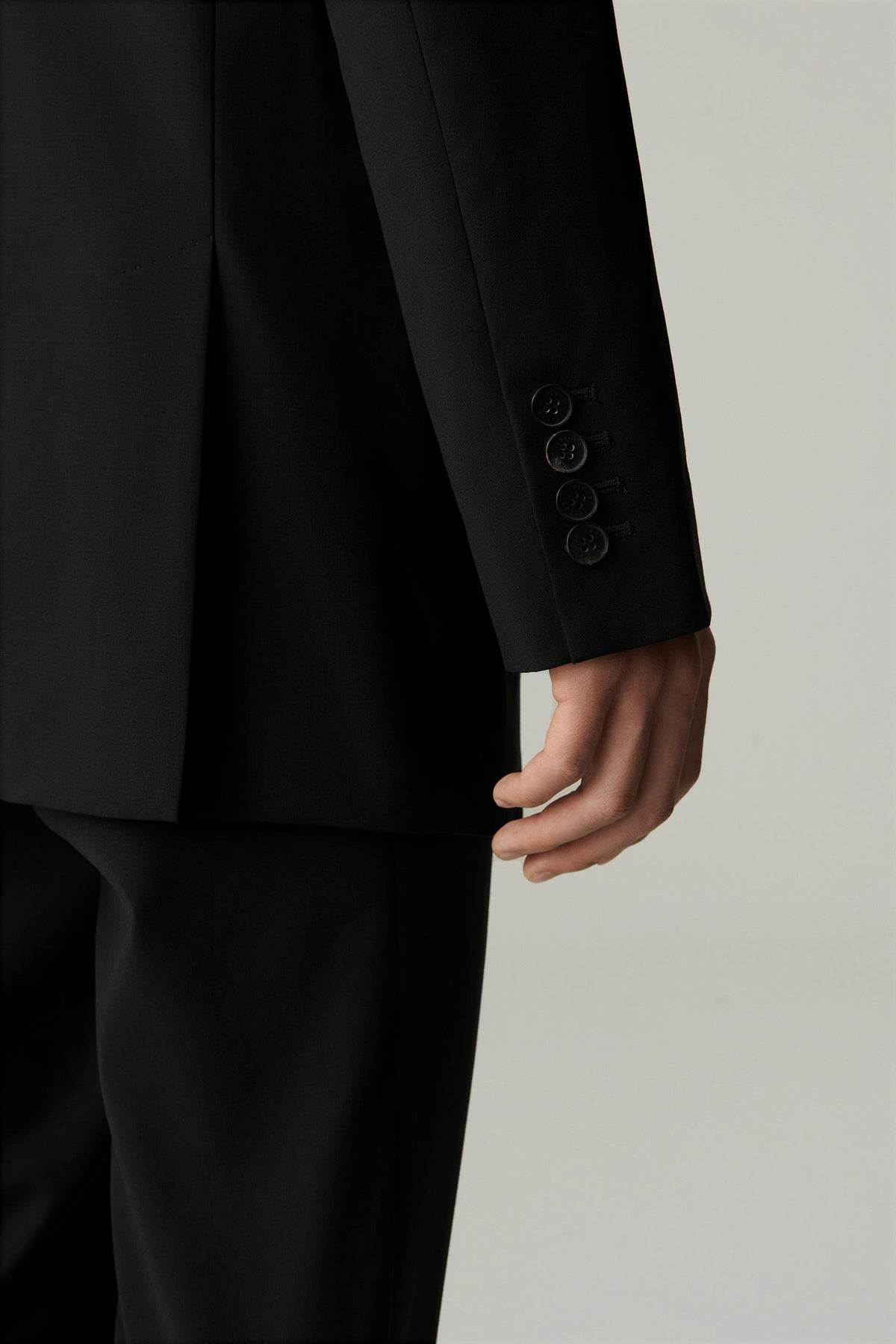 Close-up of the sleeve and cuff of the black wool blazer, showing the clean finish.