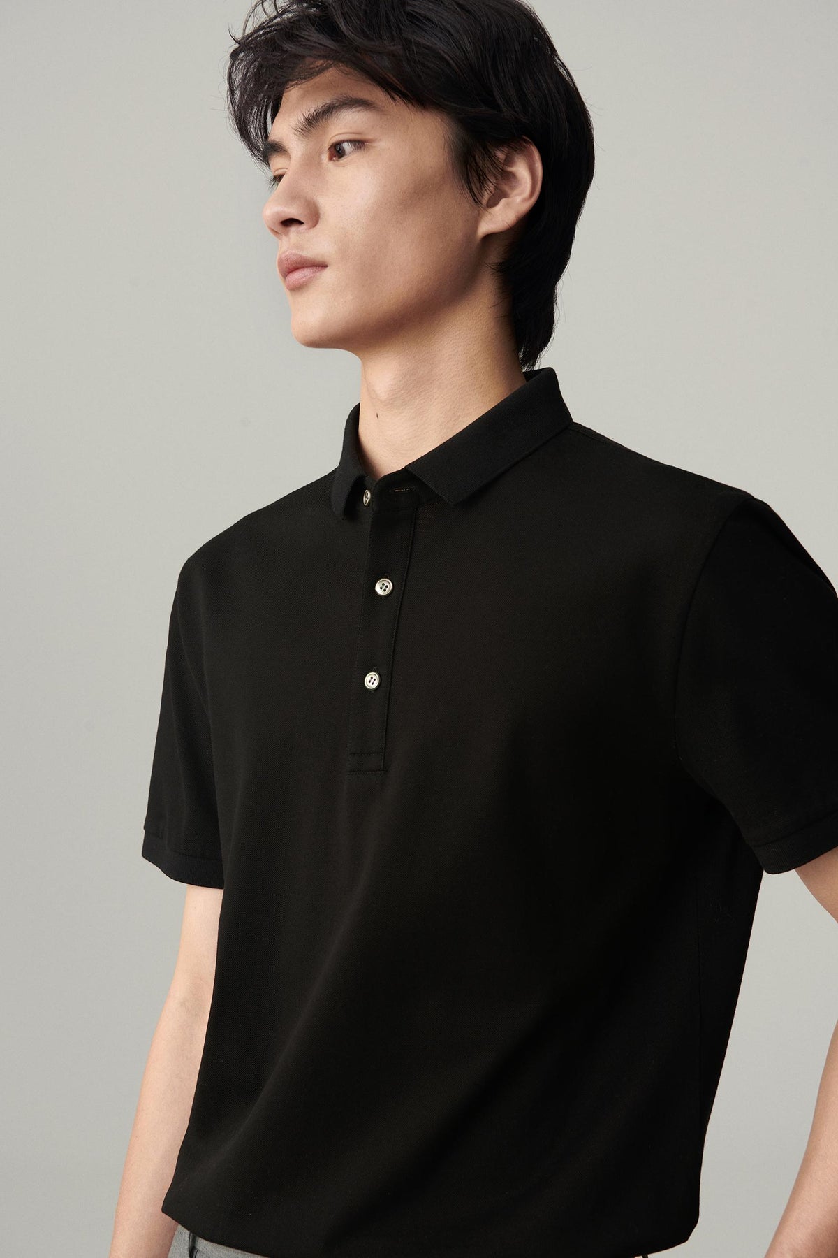Closer view of the deep black silk polo, highlighting the collar, button placket and smooth knit surface.