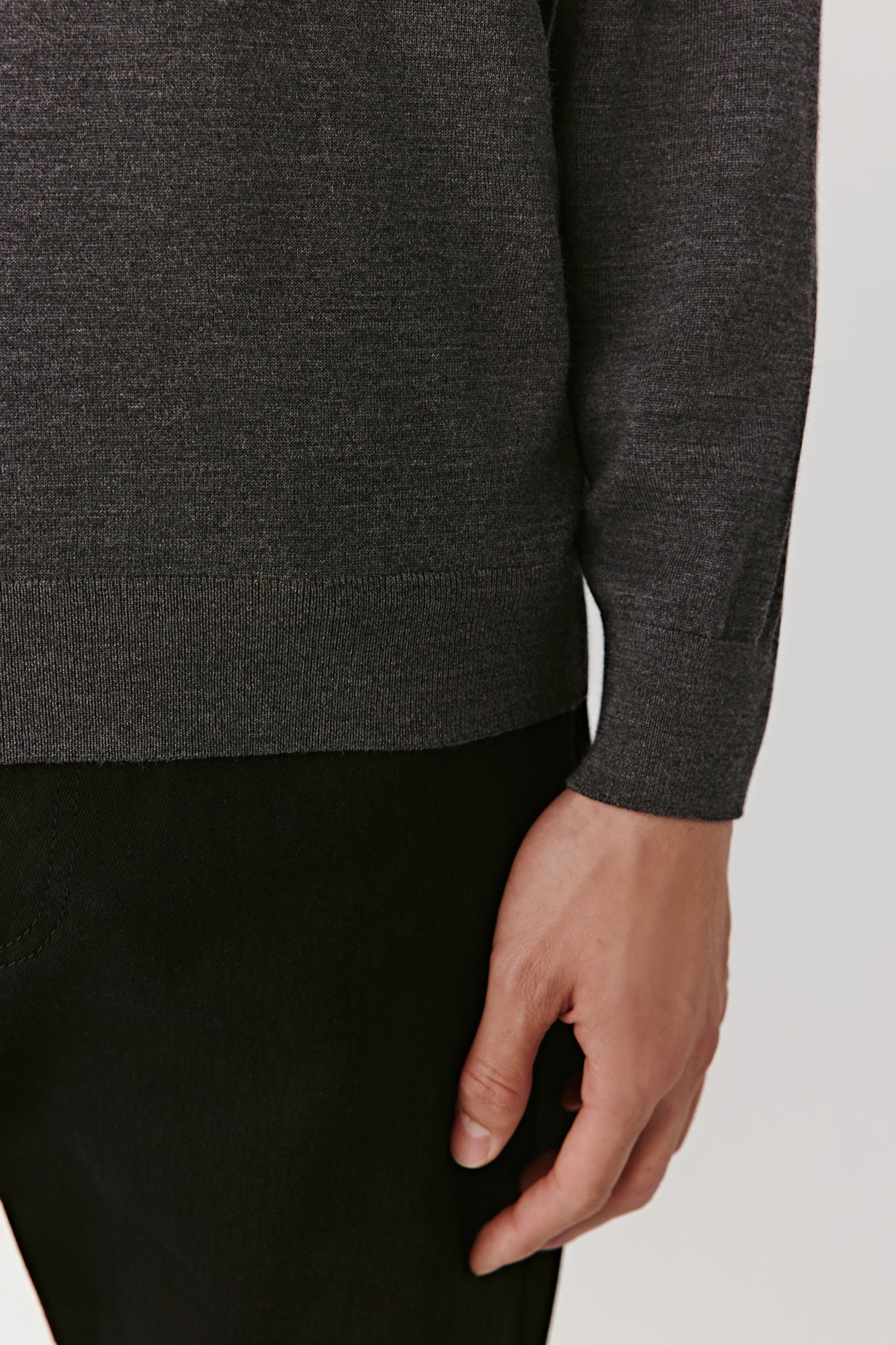 A close-up reveals the ribbed finishing at the cuffs and hem, showing discreet craftsmanship.