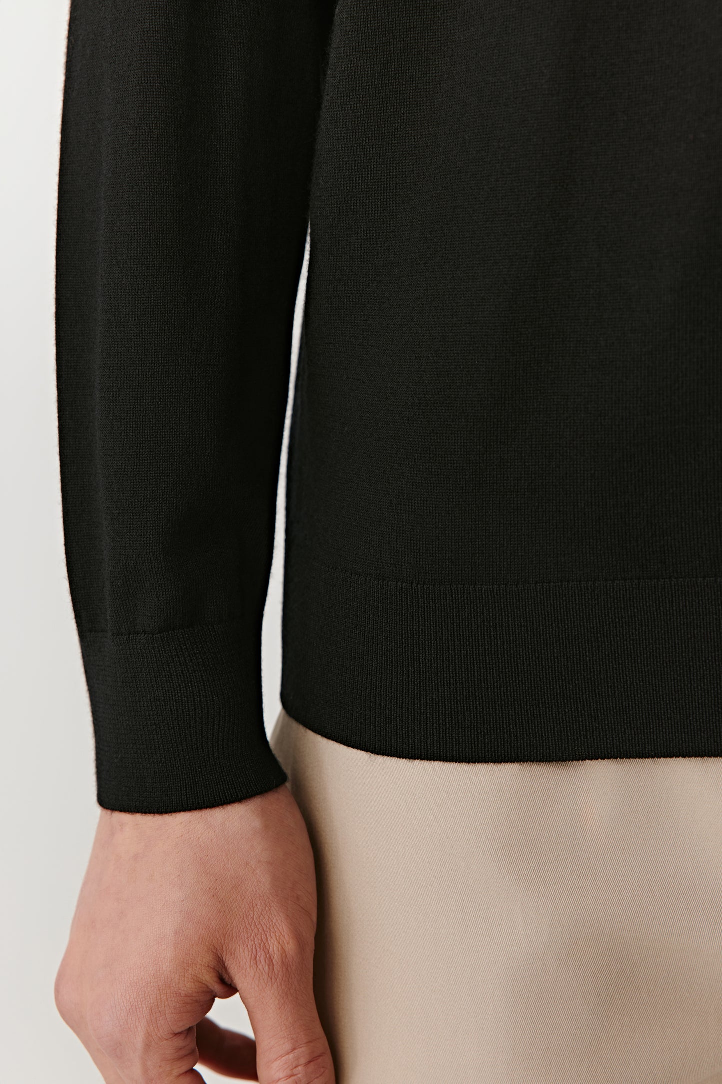 A close-up focuses on the sleeve and ribbed cuff, showing subtle craftsmanship in the details.