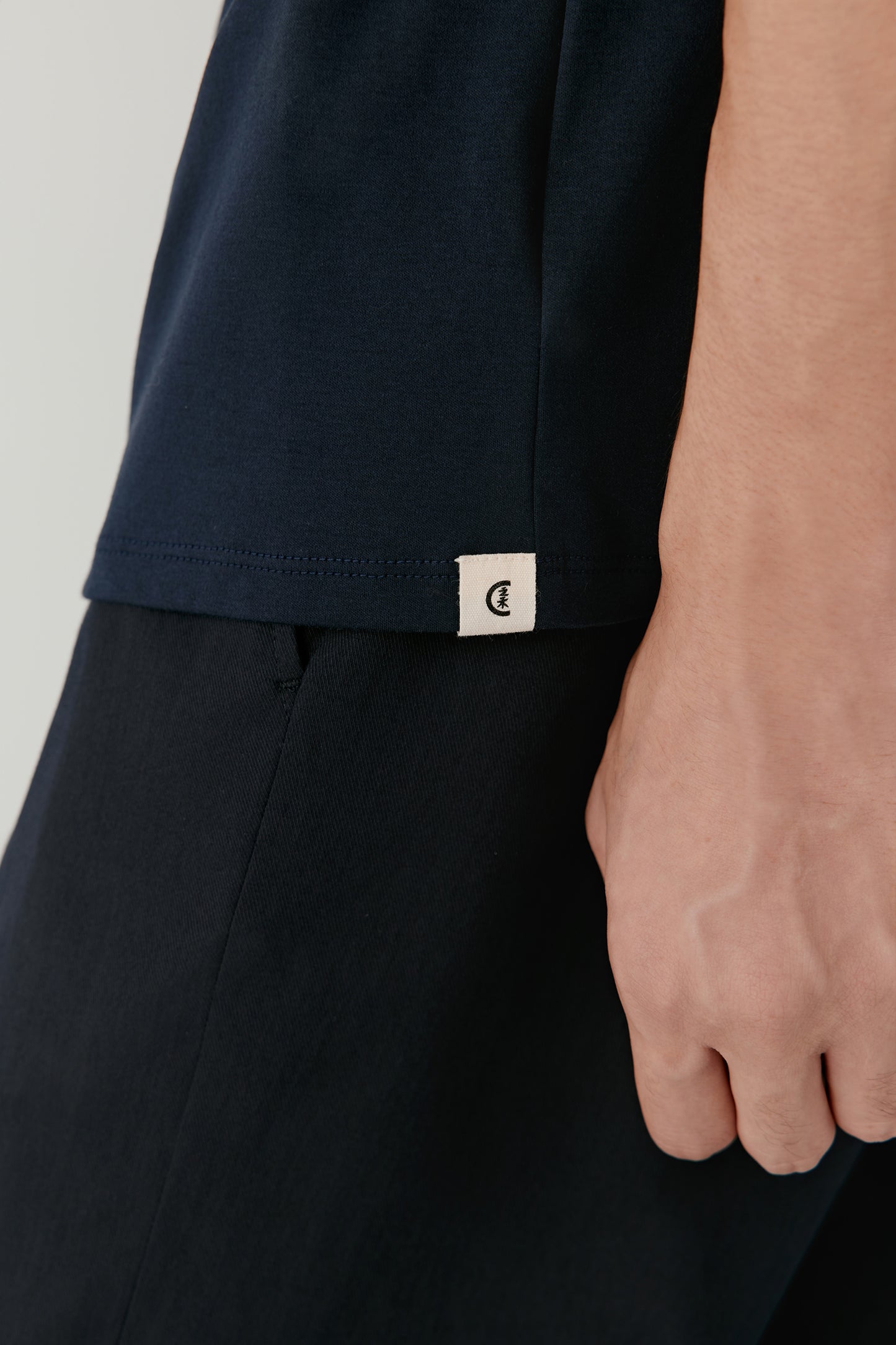 The final close-up reveals the dense cotton texture and the precise topstitching along the hem and sleeves.