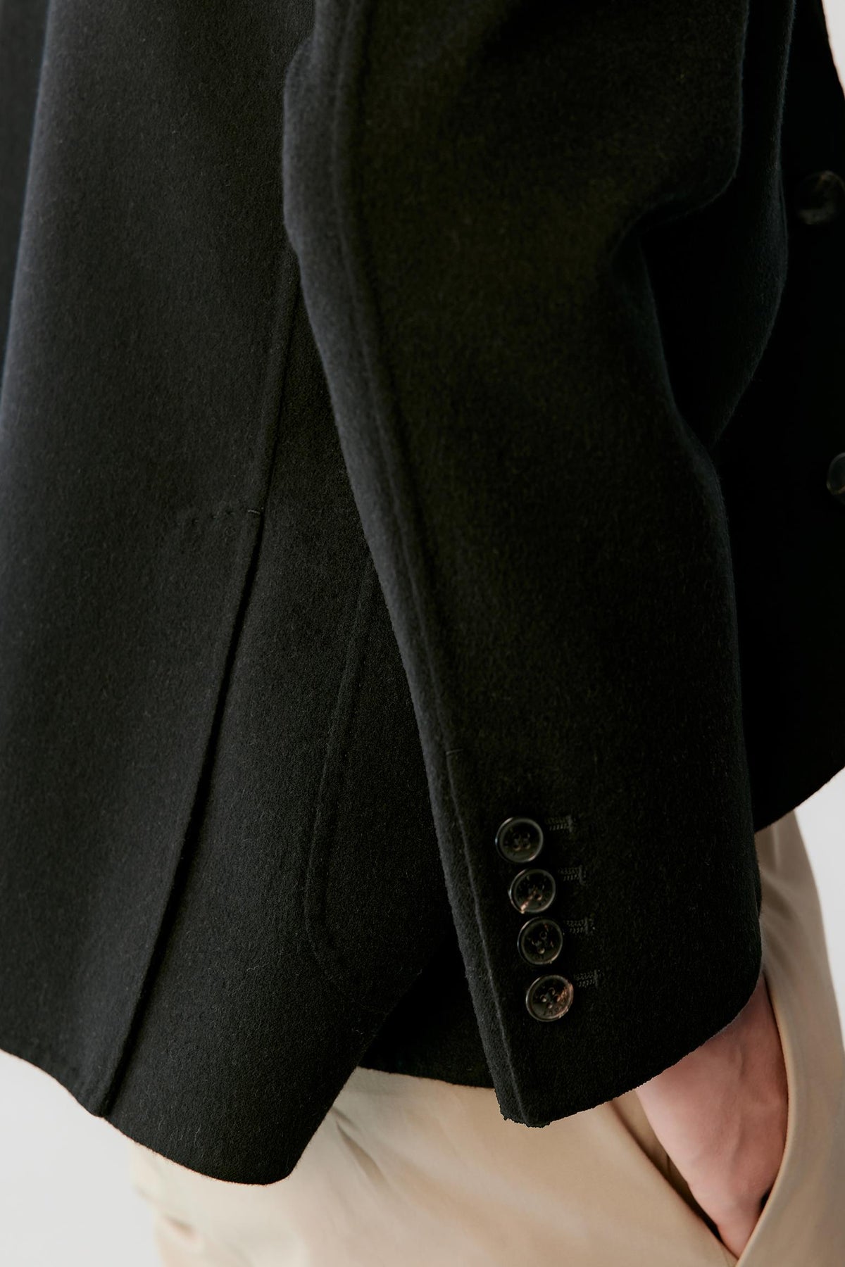 Close-up highlighting the patch pocket and smooth wool suiting surface.
