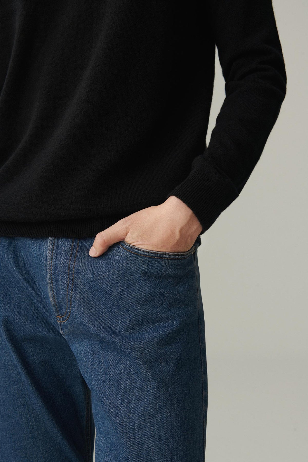 Close-up showing the ribbed hem and fine knit texture of the black cashmere pullover.