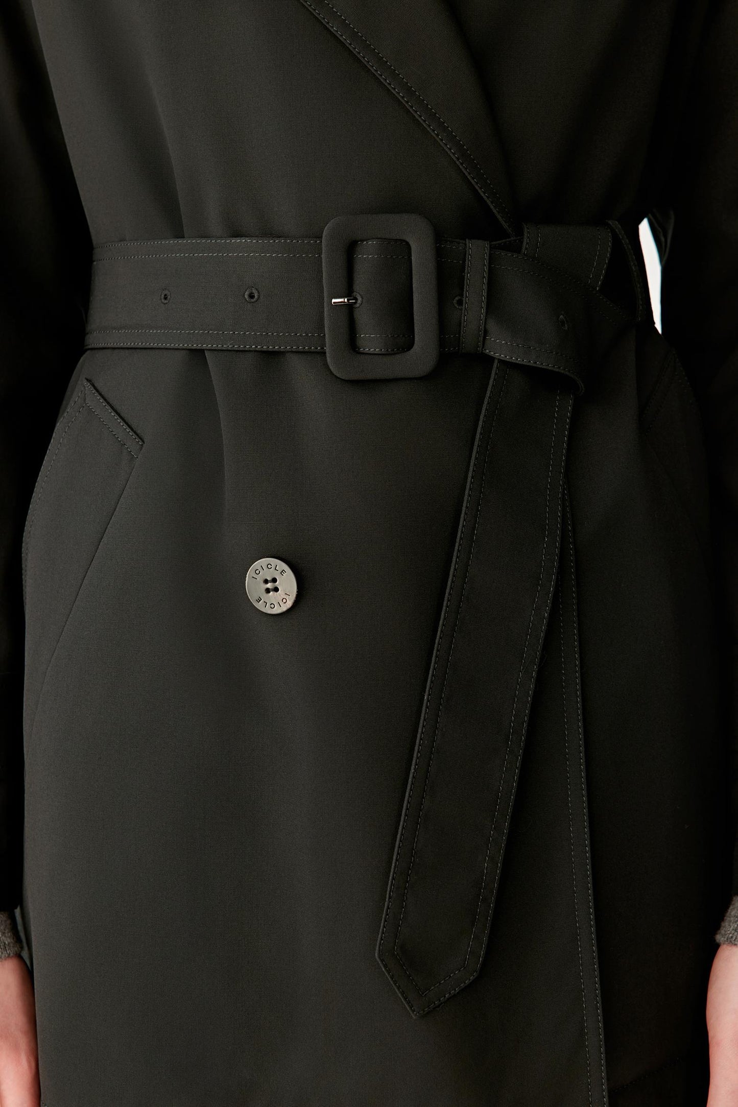 Close-up view of the waist area highlighting the self-fabric belt, belt loops and double-breasted button fastening. The image showcases the precise finishing, structured construction and subtle texture of the wool and silk fabric.