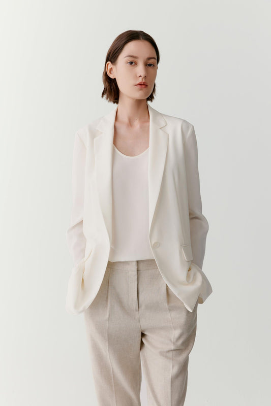 Three-quarter view showing the full silhouette and relaxed tailoring of the blazer. The image emphasizes the fluid movement of the silk crêpe de Chine, the clean lines of the construction and the balanced proportions created by the softly structured shape.