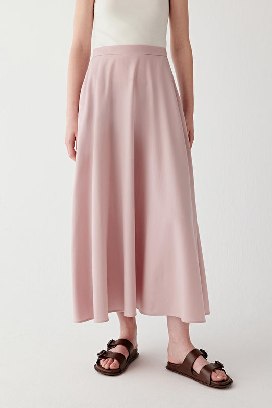 Front view highlighting the long vertical lines of the skirt and its fluid drape. The smooth waistband sits neatly at the waist while the wool twill fabric falls in soft folds toward the hem. The lightweight structure of the fabric allows gentle movement while maintaining a clean silhouette.