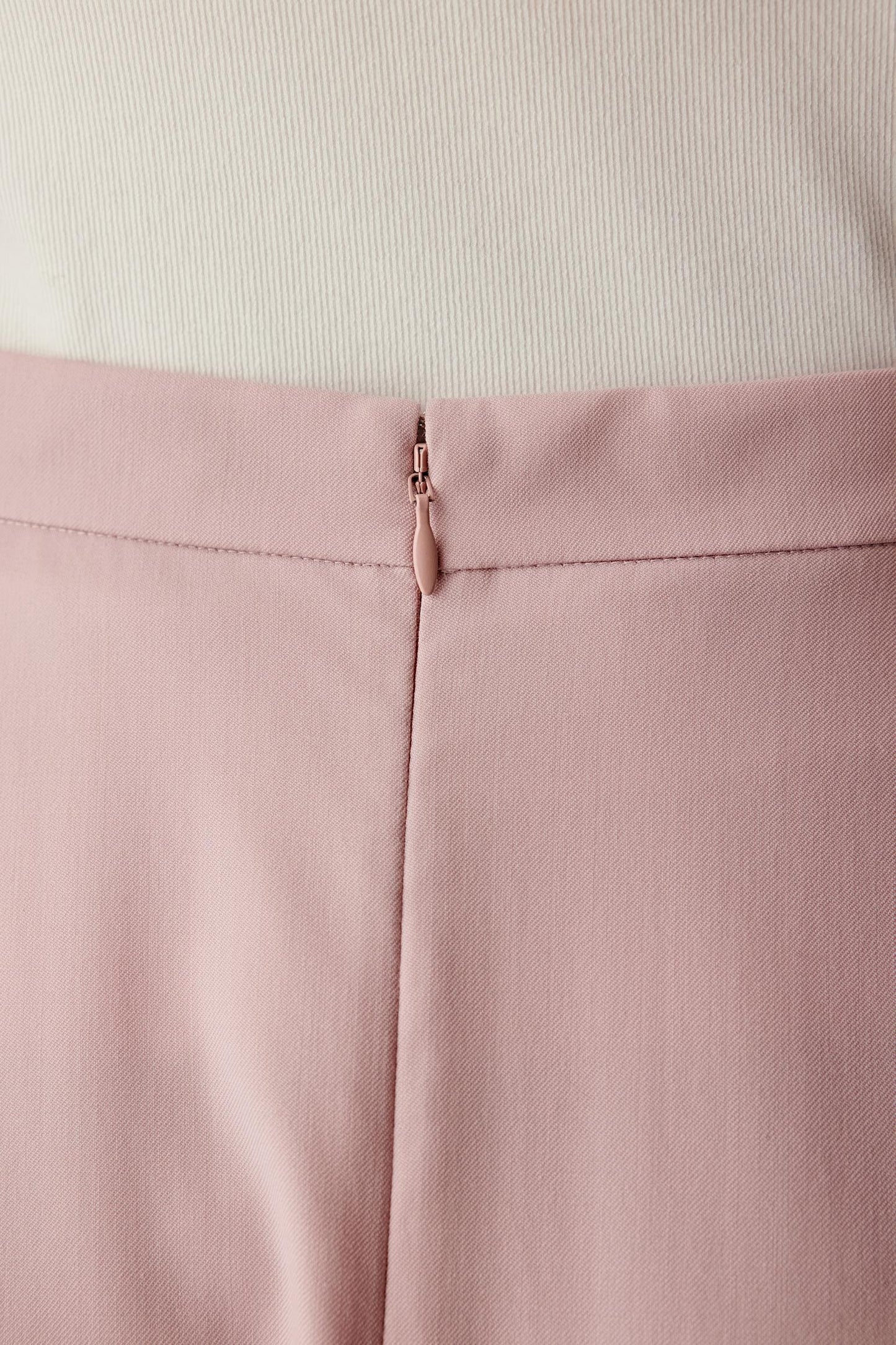 Close-up of the lower hem and fabric surface, showing the fine wool twill texture and soft flow.