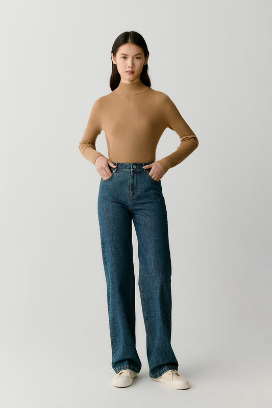Full-length front view showing the fitted pullover styled with blue jeans. The ribbed knit structure creates vertical lines that enhance the slim silhouette of the sweater.