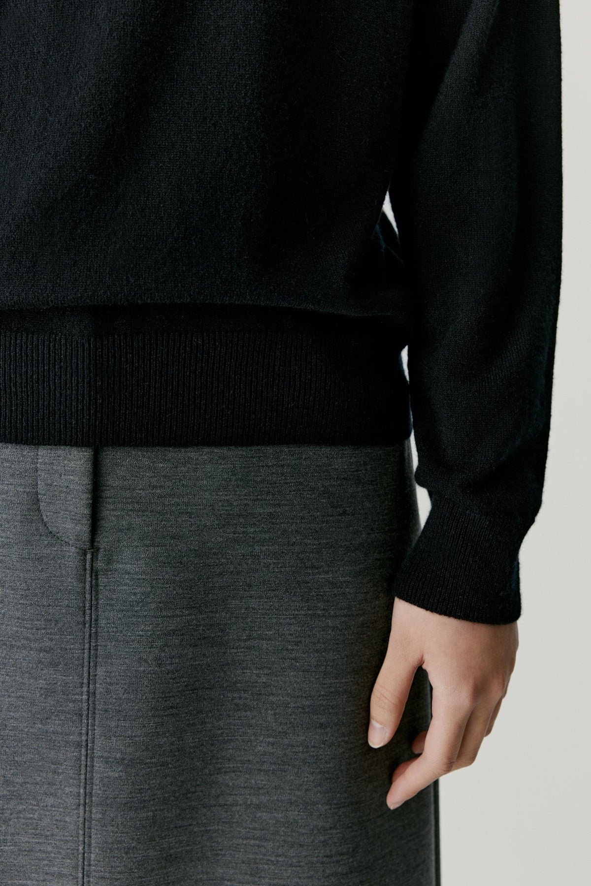 Close-up highlighting the long sleeve, ribbed cuff and fine-knit texture of the deep black cashmere pullover.