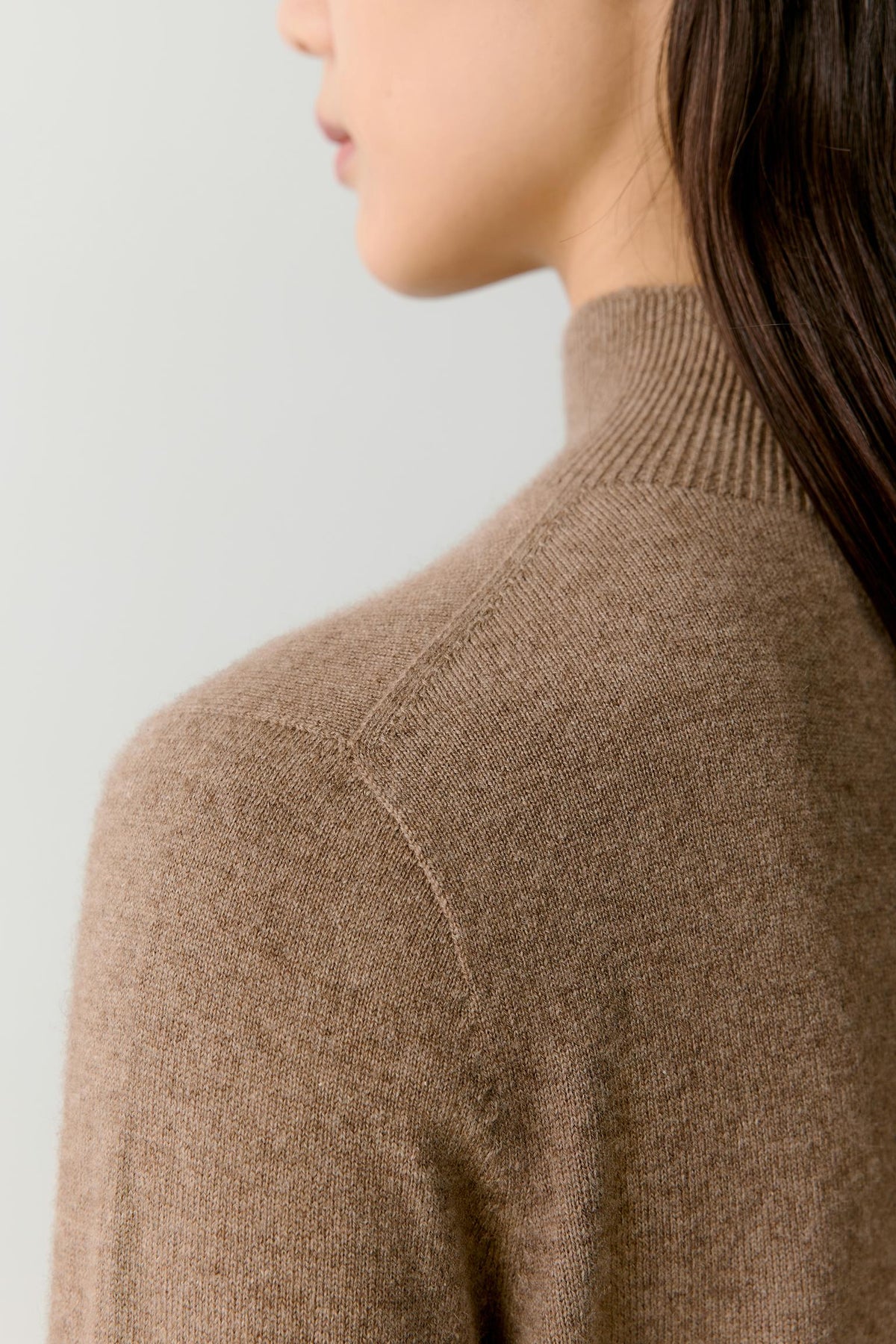 Close-up highlighting the mock neck, shoulder construction and soft taupe melange cashmere surface.