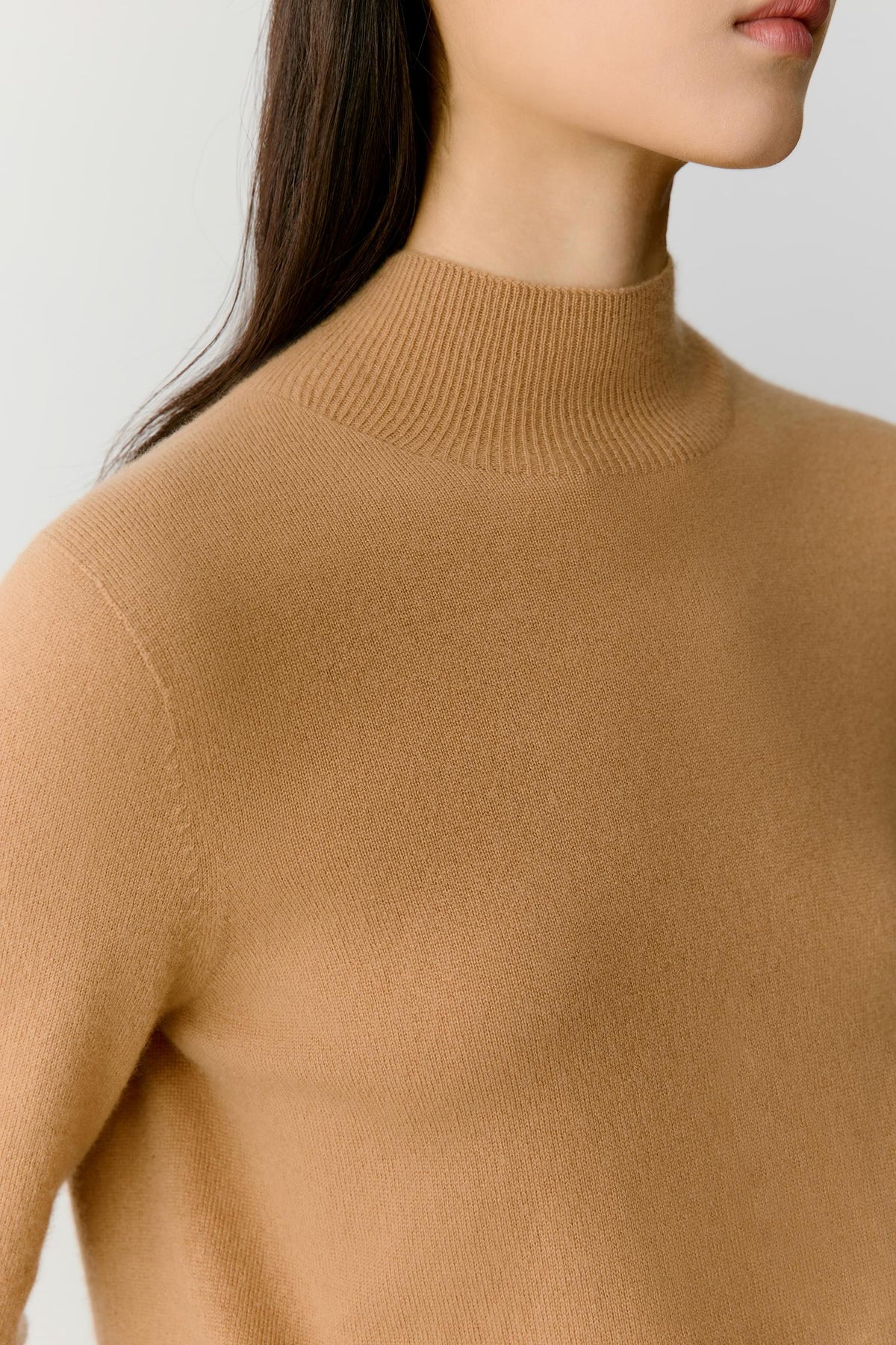 Close-up highlighting the dropped shoulder, long sleeve and smooth camel cashmere surface.
