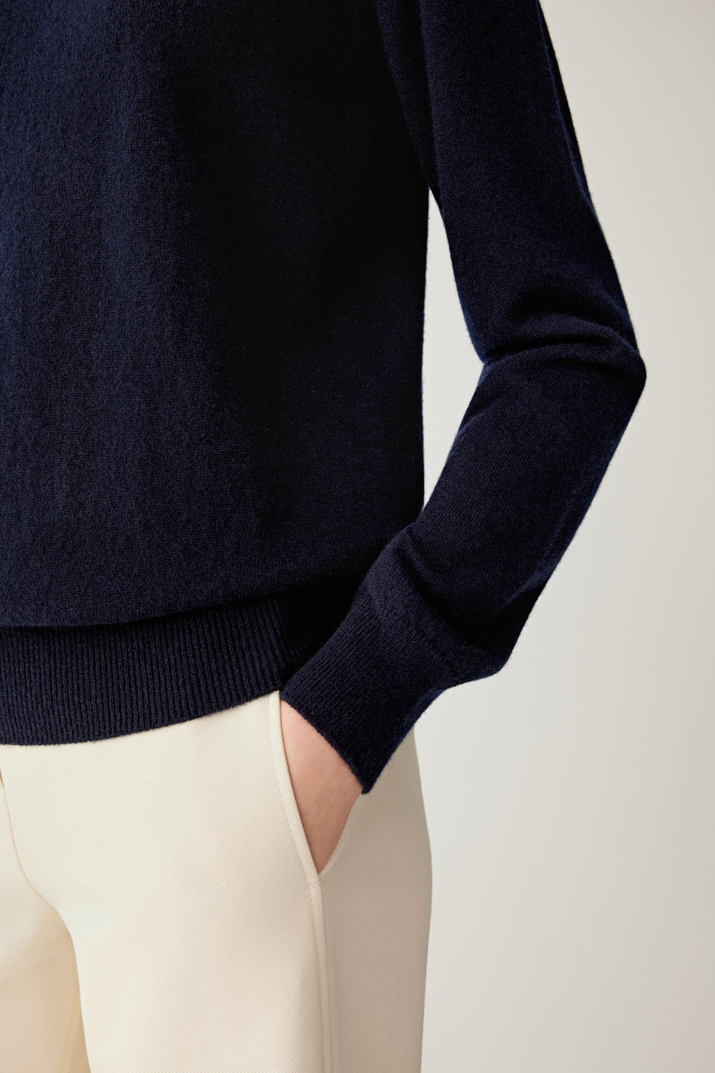 Close-up of navy cashmere pullover showing the long sleeve, ribbed cuff and hem detail