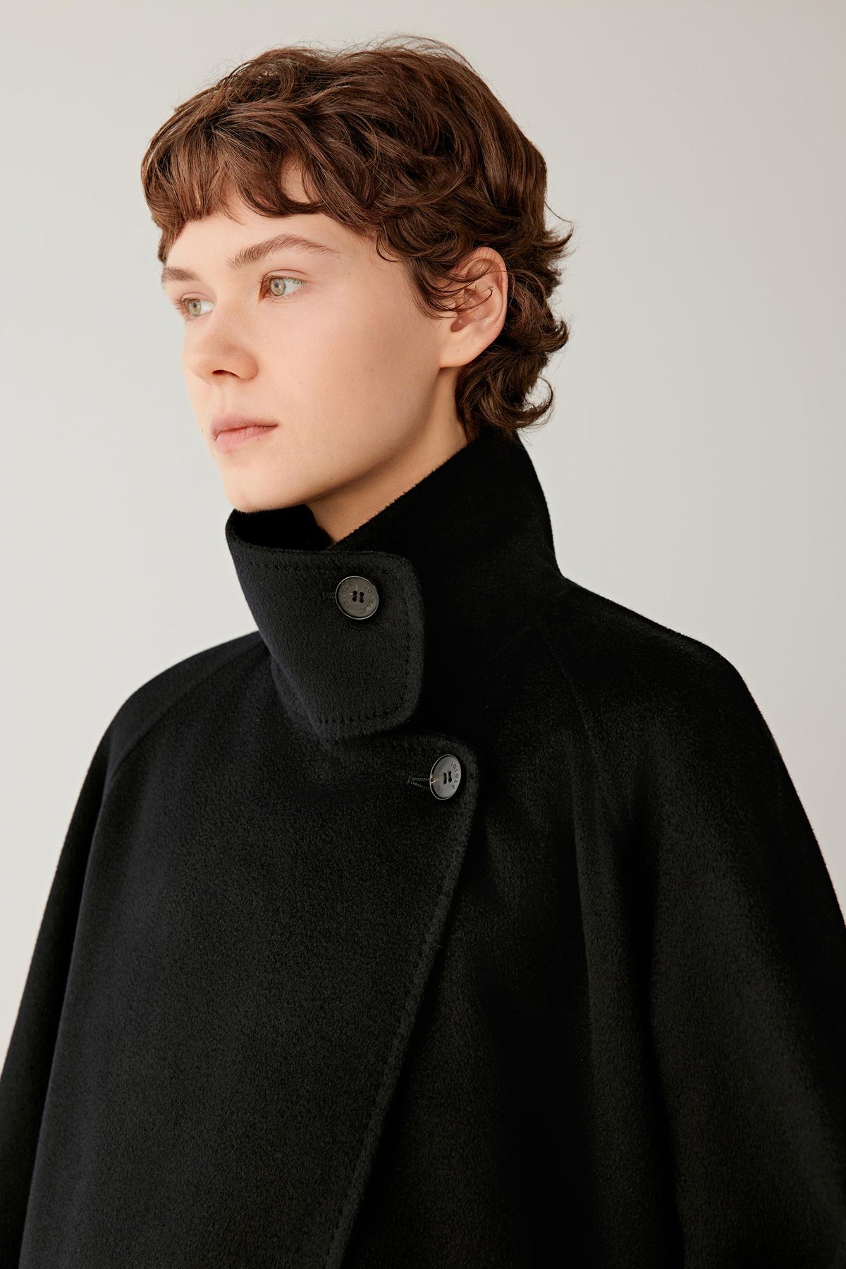 Close-up highlighting the high stand collar and soft deep black cashmere surface.