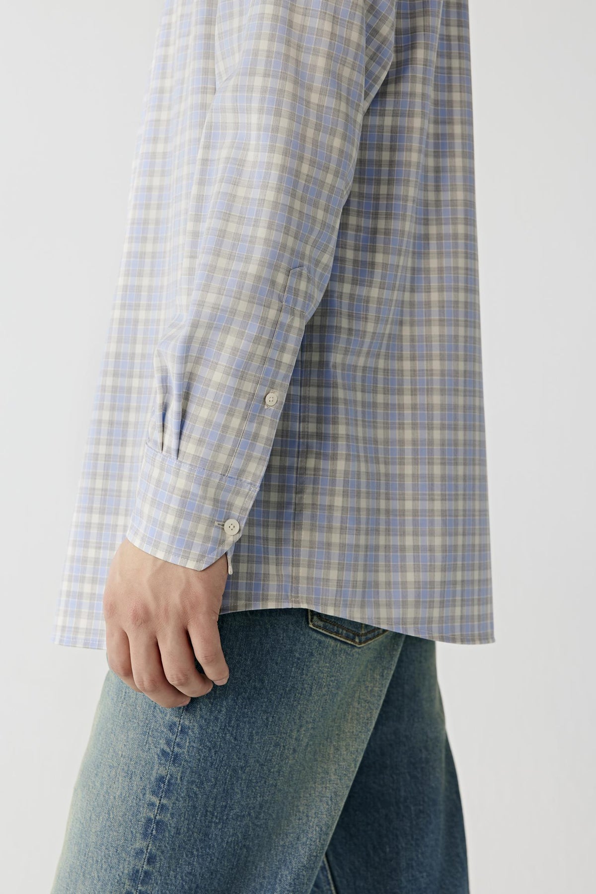Close-up highlighting the long sleeve, buttoned cuff and lightweight checked worsted wool fabric.