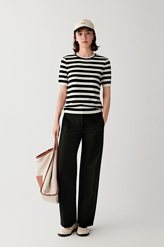 Full-length front view showing the fitted silhouette of the striped wool and silk pullover worn with straight black trousers. The horizontal stripe pattern runs evenly across the torso and sleeves.