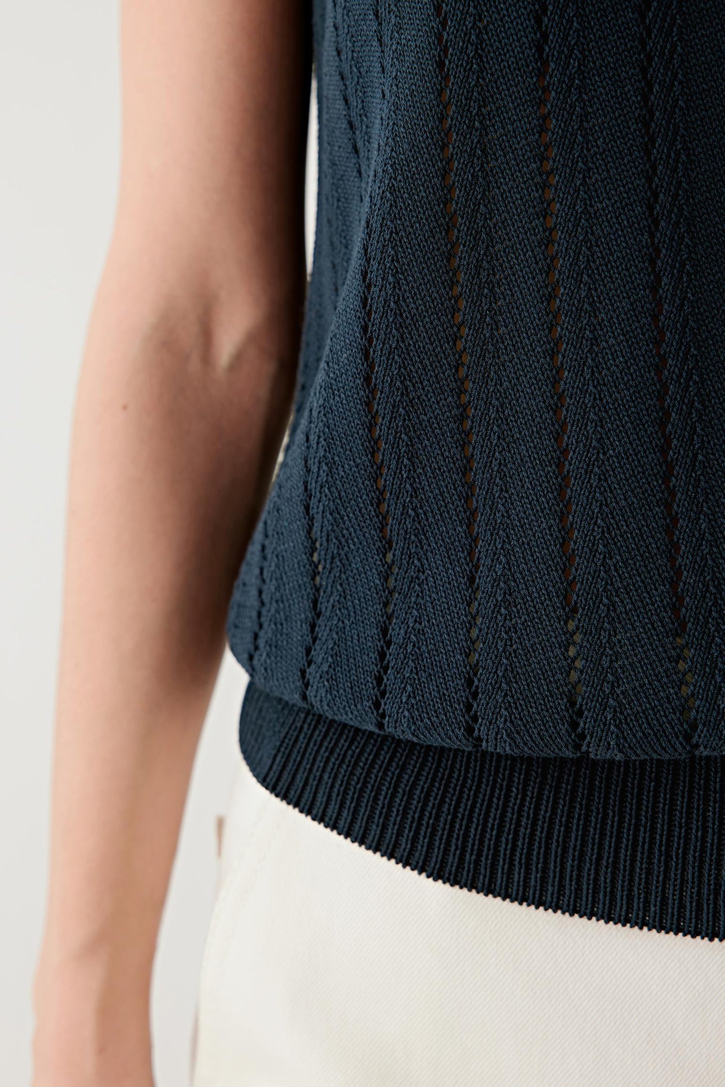 Close-up of the lower hem and side area, highlighting the finely ribbed hem finish, the vertical knit construction and the texture of the silk and cotton yarn blend