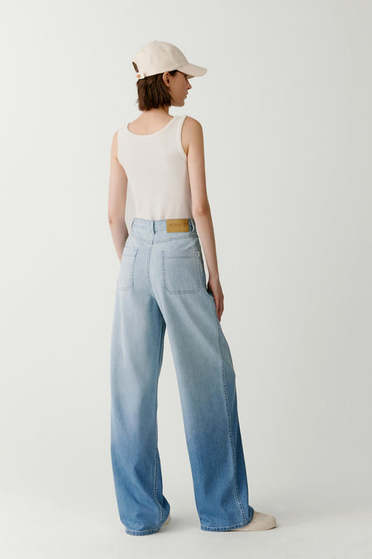 Three-quarter view highlighting the generous width of the legs and the fluid drape of the lightweight denim fabric.