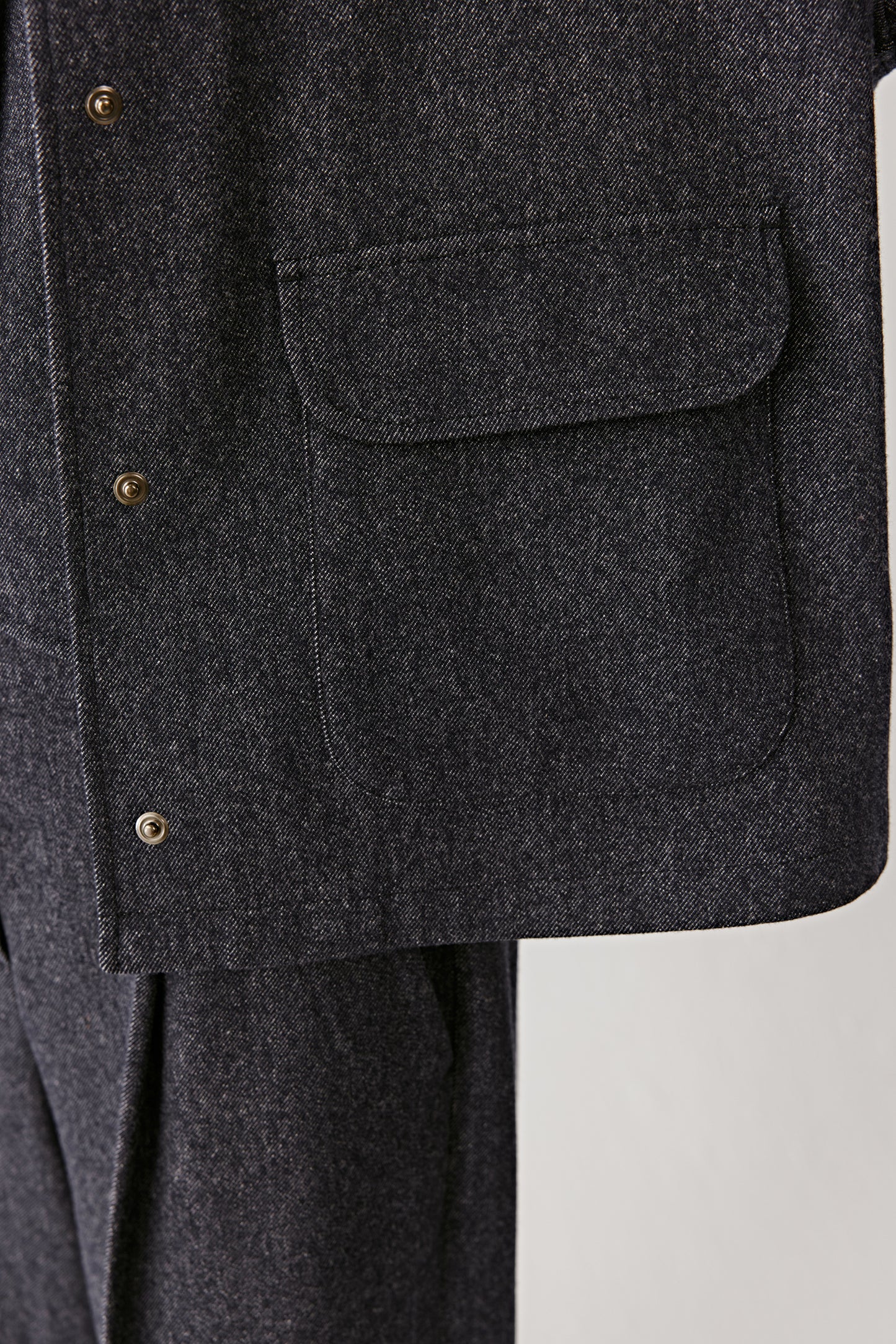 A close-up reveals the Super 150s wool weave and subtle denim-effect finish under soft light.