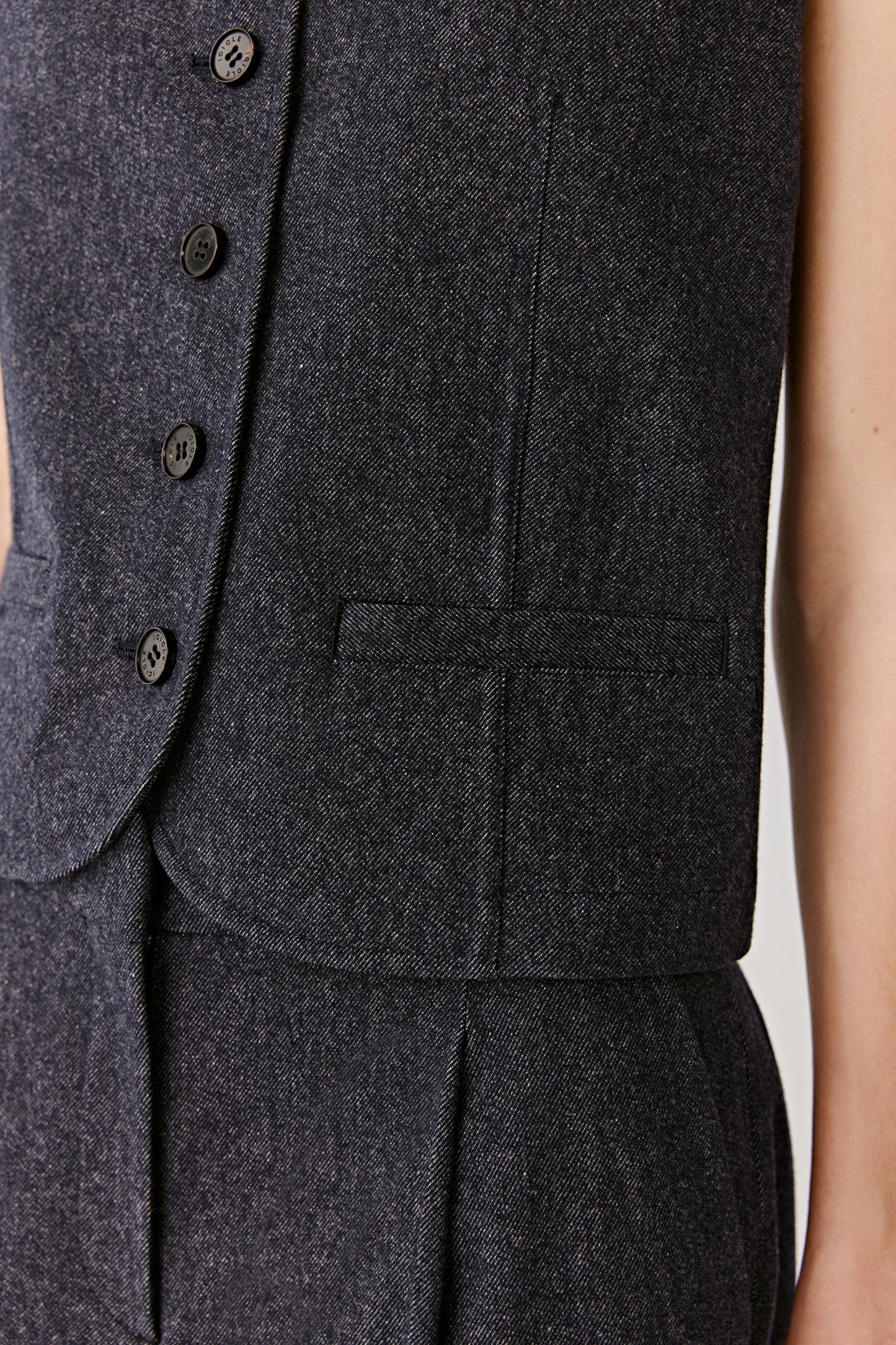 A close-up highlights the fine weave of the wool and the refined detailing of the button placket and seams.