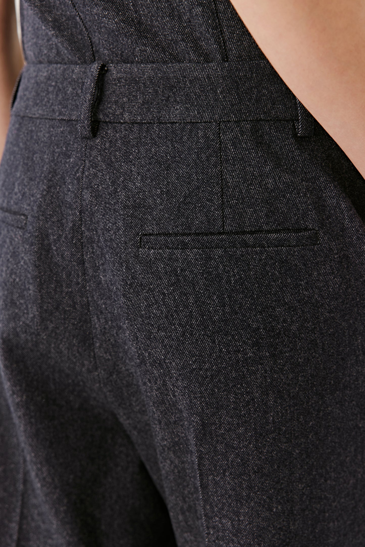 A close-up focuses on the waistband and side pocket, showing precise tailoring and neat stitching.