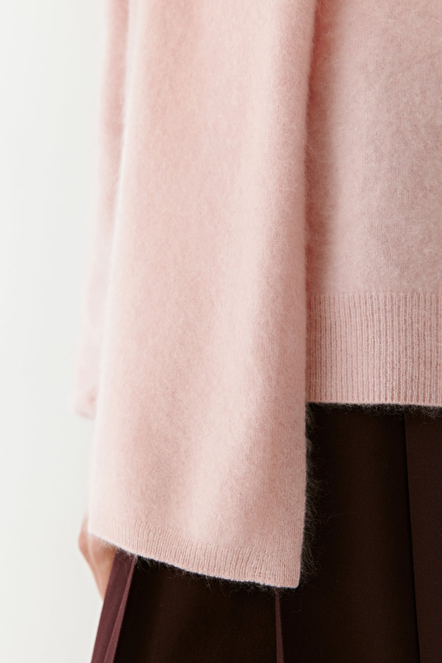 Close-up of a soft pink knit scarf with textured detail on a light background