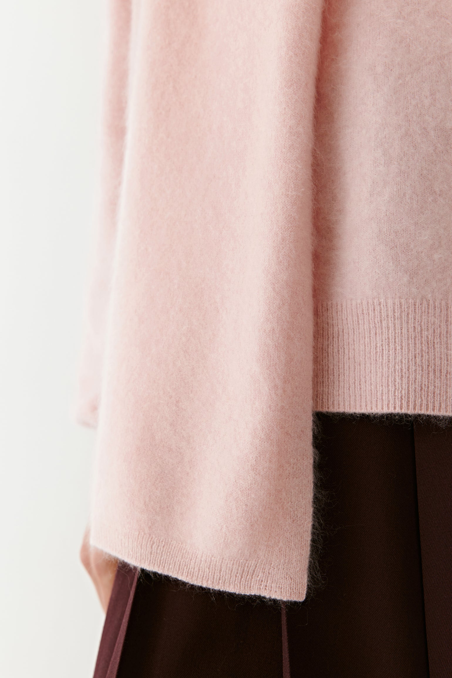 Close-up of a soft pink knit scarf with textured detail on a light background