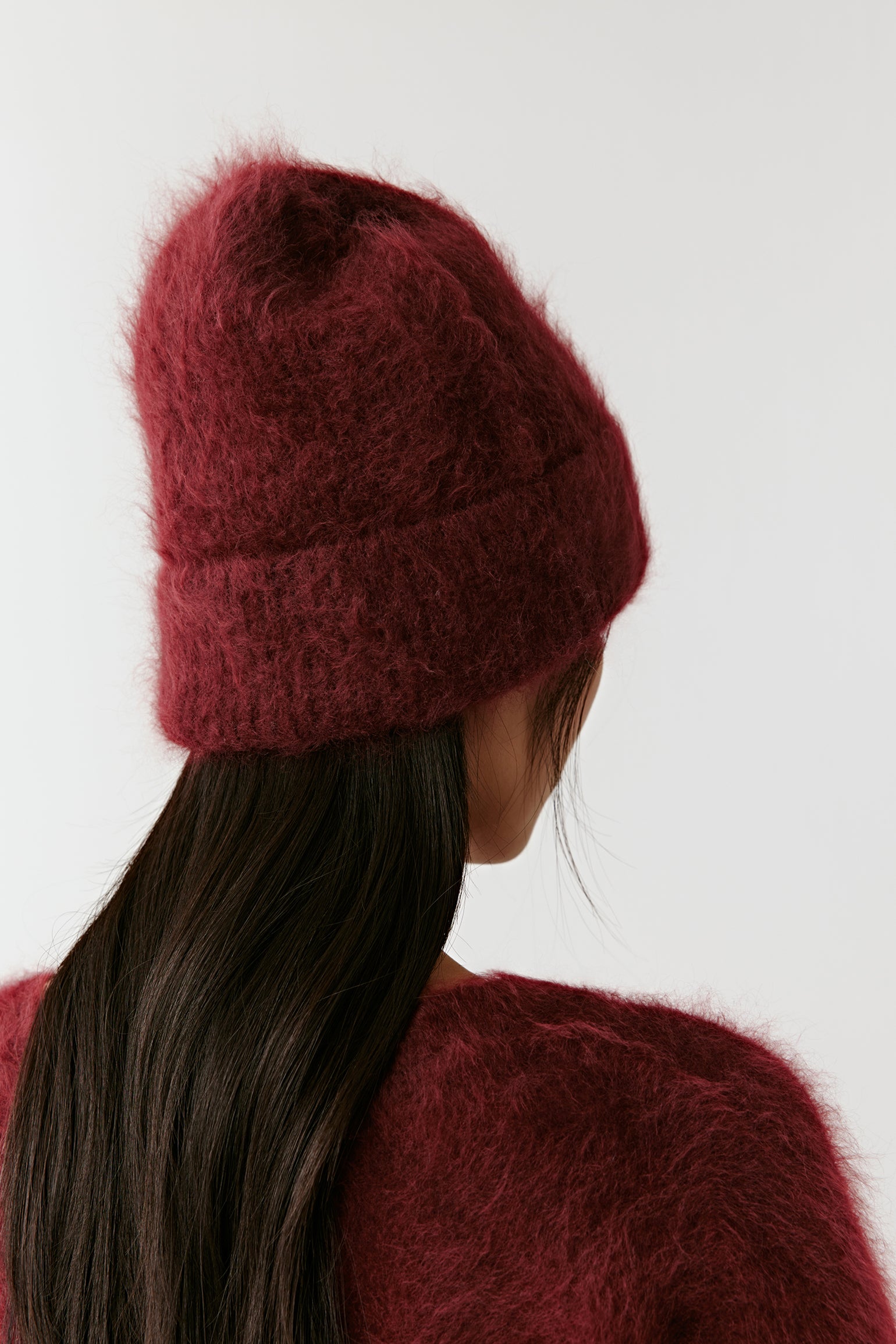 Back view of a burgundy knit beanie on a light background