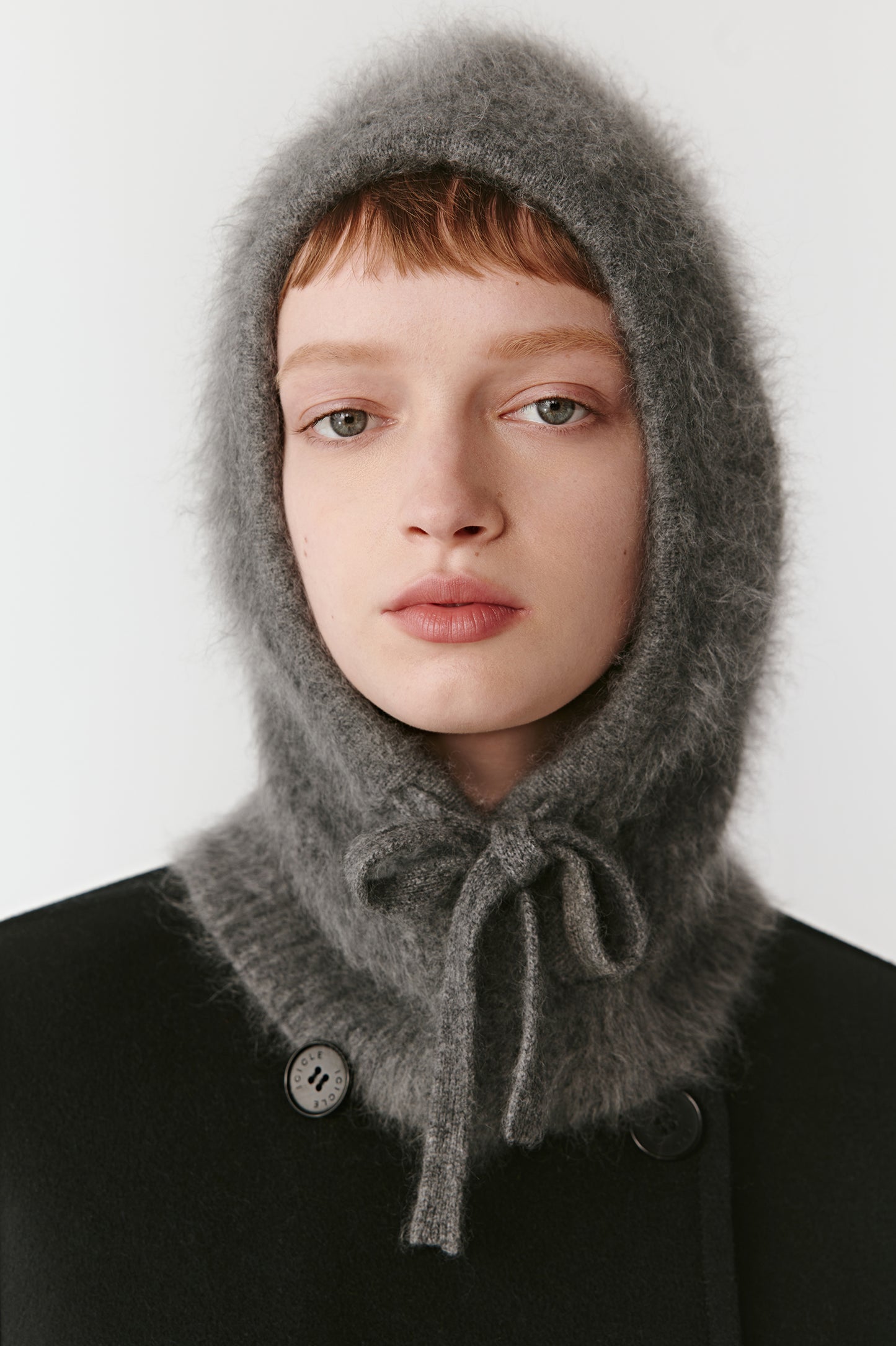 Front view of a grey knit hood with ties on a light background