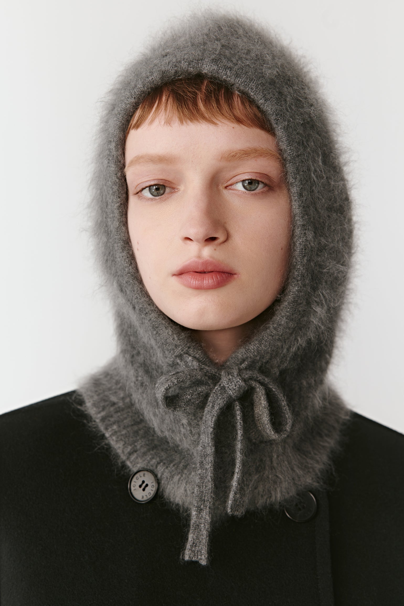 Front view of a grey knit hood with ties on a light background