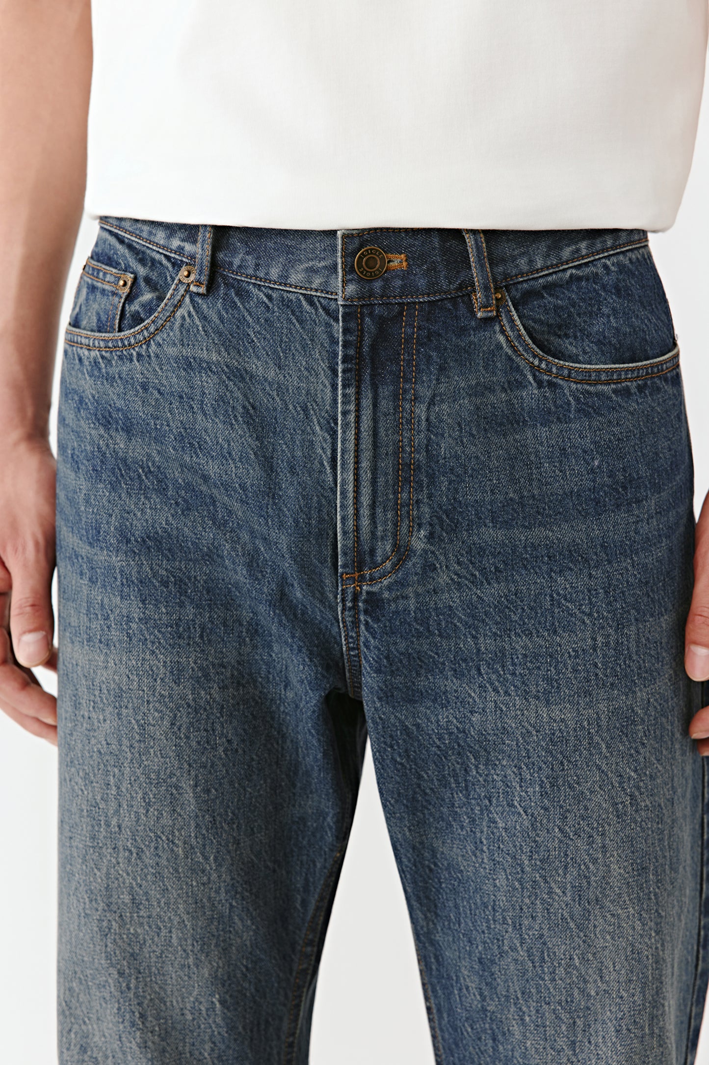 A close-up captures the contrast stitching and metal button closure.