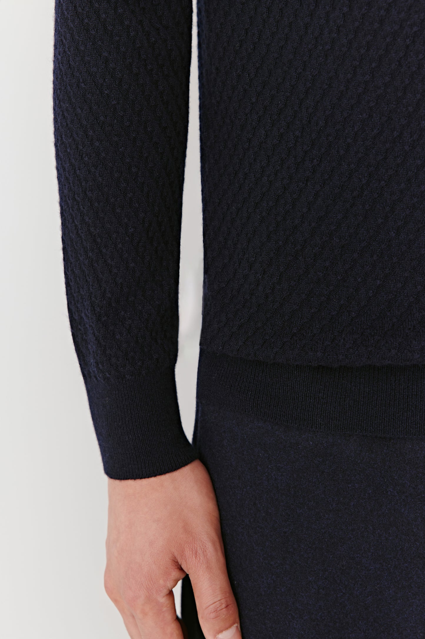 Close-up of the sleeve and hem showing the smooth knit finish.