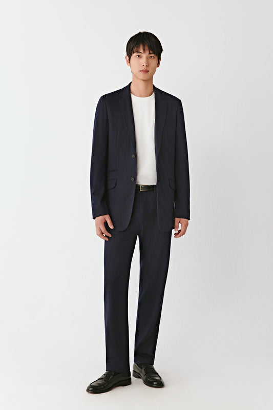 Full-length image of a man wearing a navy wool jersey blazer with dark trousers for a sophisticated tailored look.