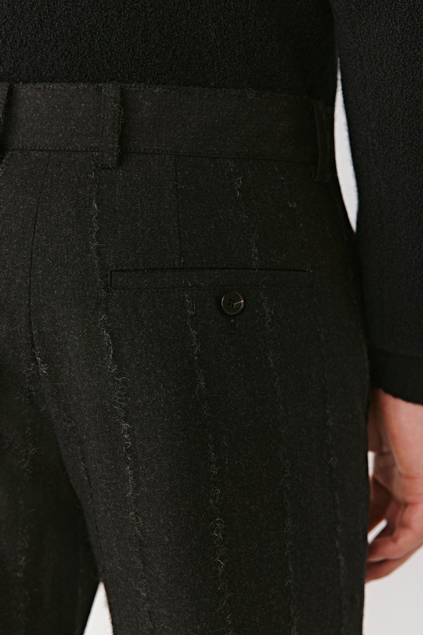Detail close-up of the side pocket and fabric texture of the pinstripe wool-blend trousers.