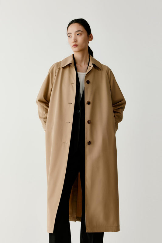 Three-quarter view of the coat worn open, revealing the inner structure and the fluid fall of the wool and silk fabric.