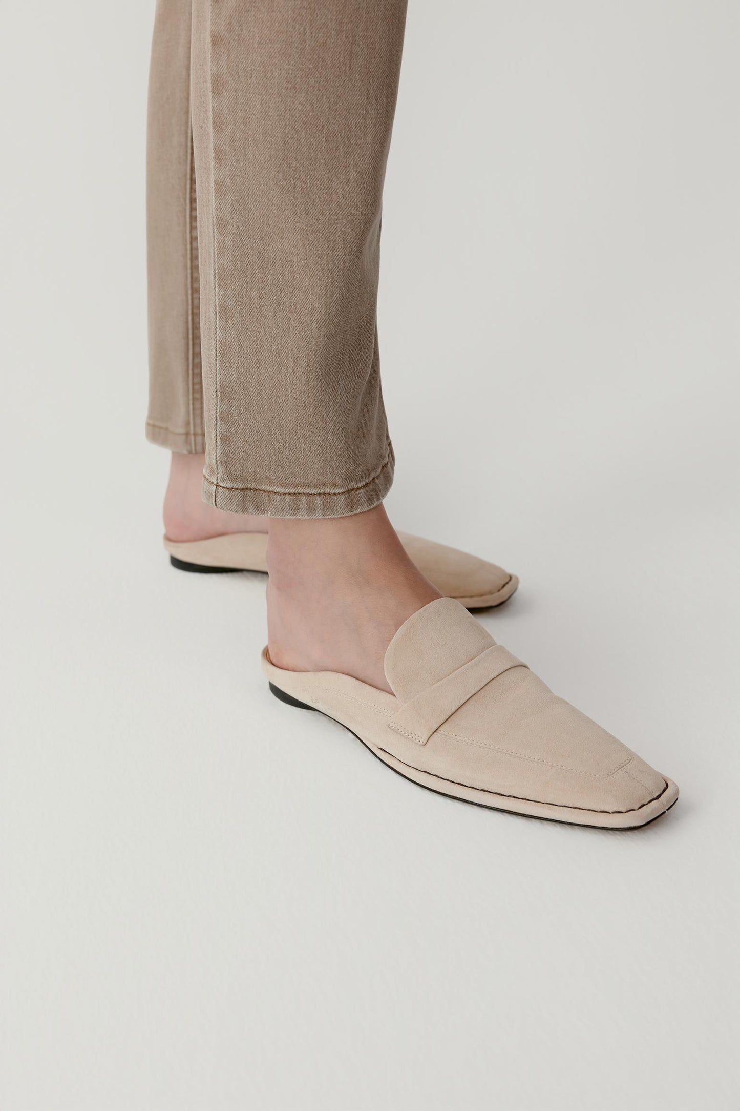 Side view showing the backless silhouette and slim sole. The supple suede construction gives the mules a relaxed, lightweight feel.