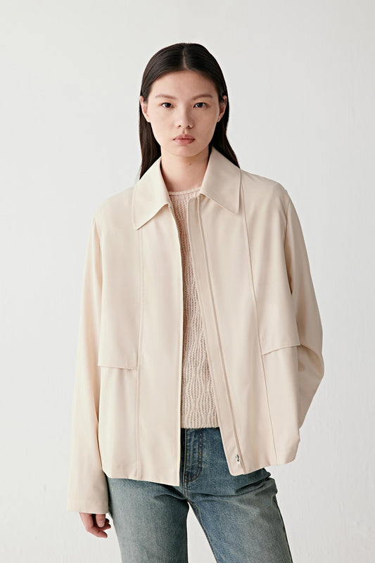Front view of the ivory wool jacket showing the relaxed cut through the body, the straight hemline at hip level and the smooth texture of the wool fabric.