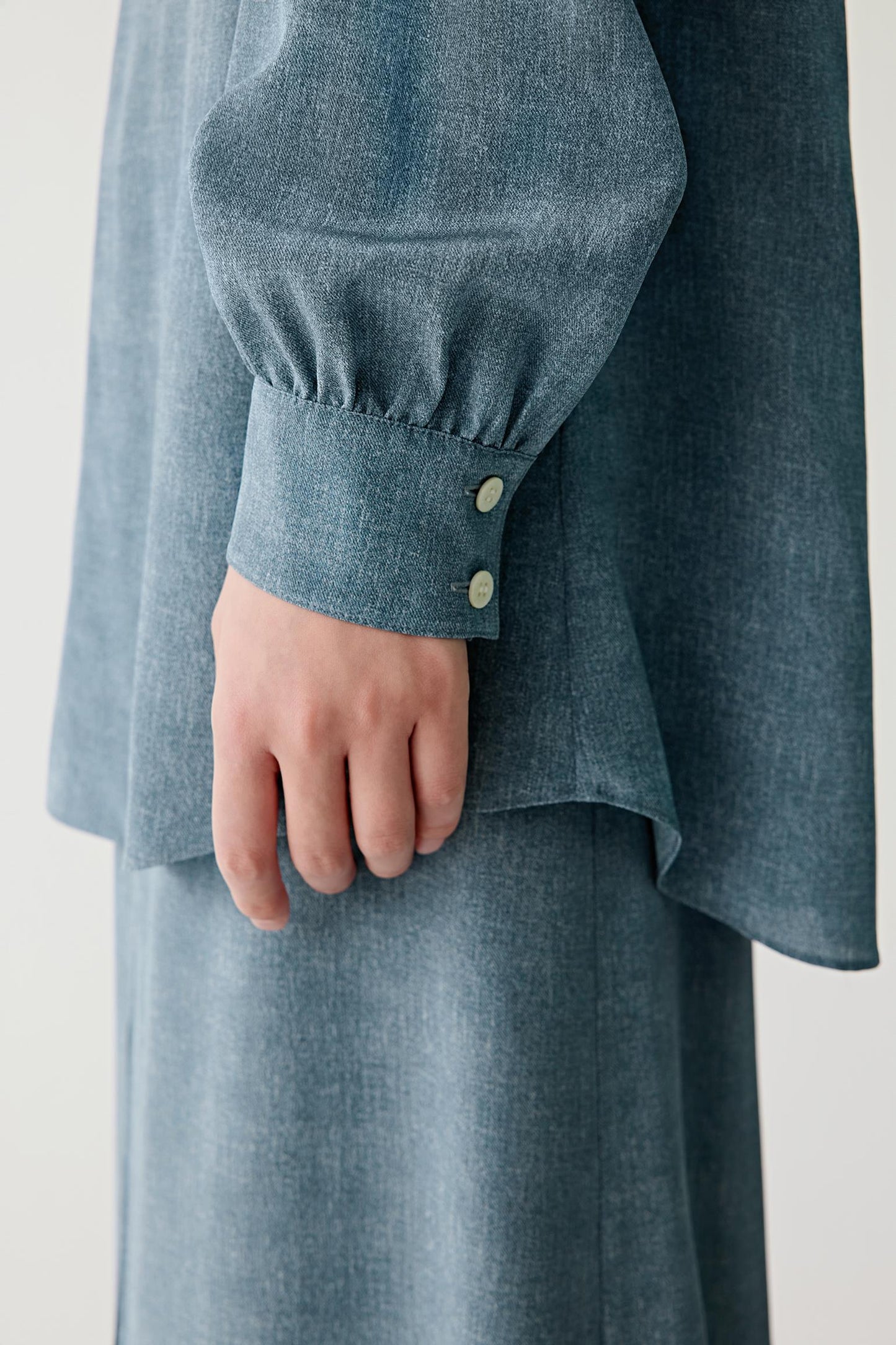 Close-up of sleeve and cuff showing the wide cuff construction, visible stitching and the softly flowing texture of the indigo blue silk fabric