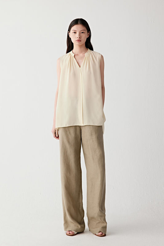 Full-length view showing the blouse paired with relaxed trousers. The image emphasizes the lightweight construction, fluid movement and soft fall of the silk fabric, illustrating the effortless drape of the silhouette.