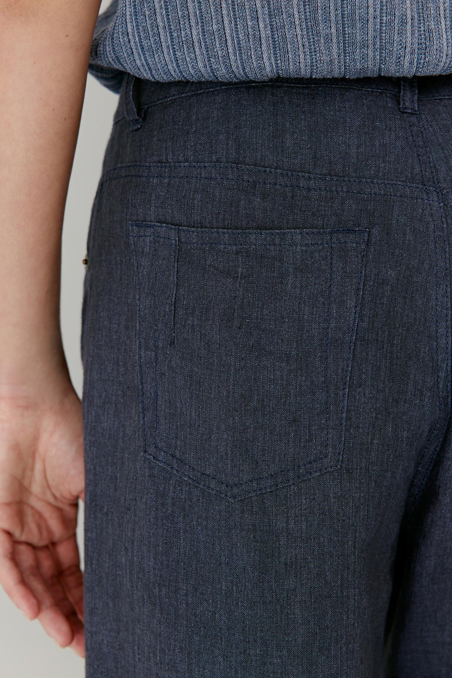 Close-up side view focusing on the hip and side pocket area. The image showcases the clean finishing, structured waistband and lightly textured linen weave, revealing the natural irregularity and depth of the fabric while maintaining a refined silhouette.